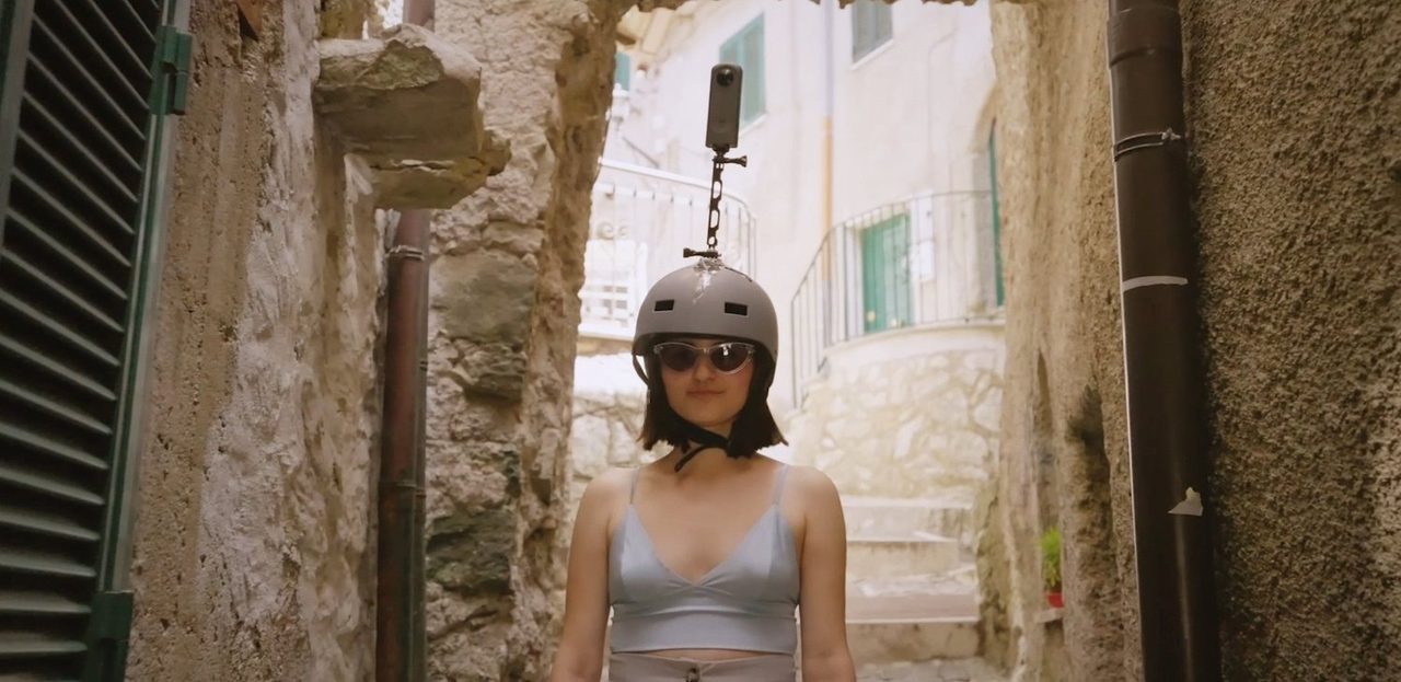 A helmet-mounted 360-degree camera worn in a narrow stone alley in Guadagnolo