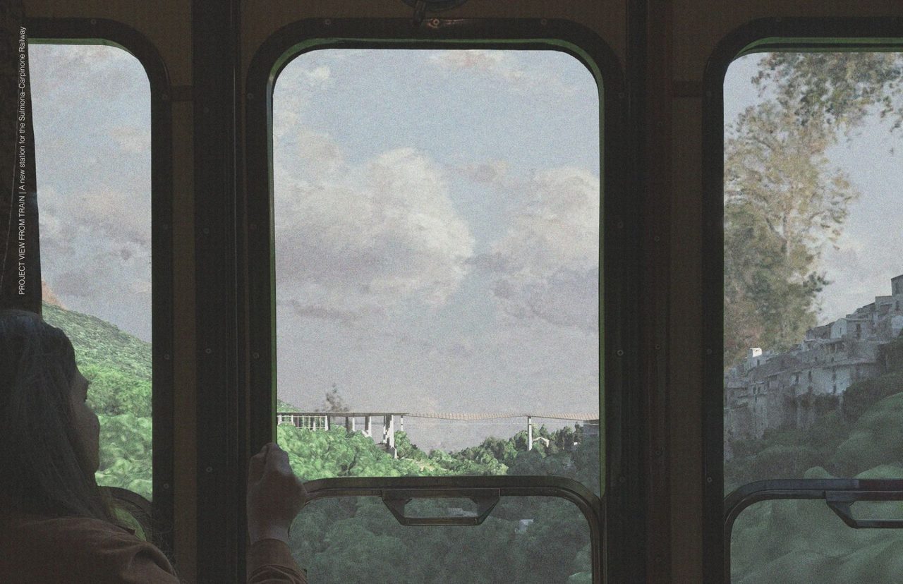 View through the windows of a train carriage onto green slopes and a hilltop village